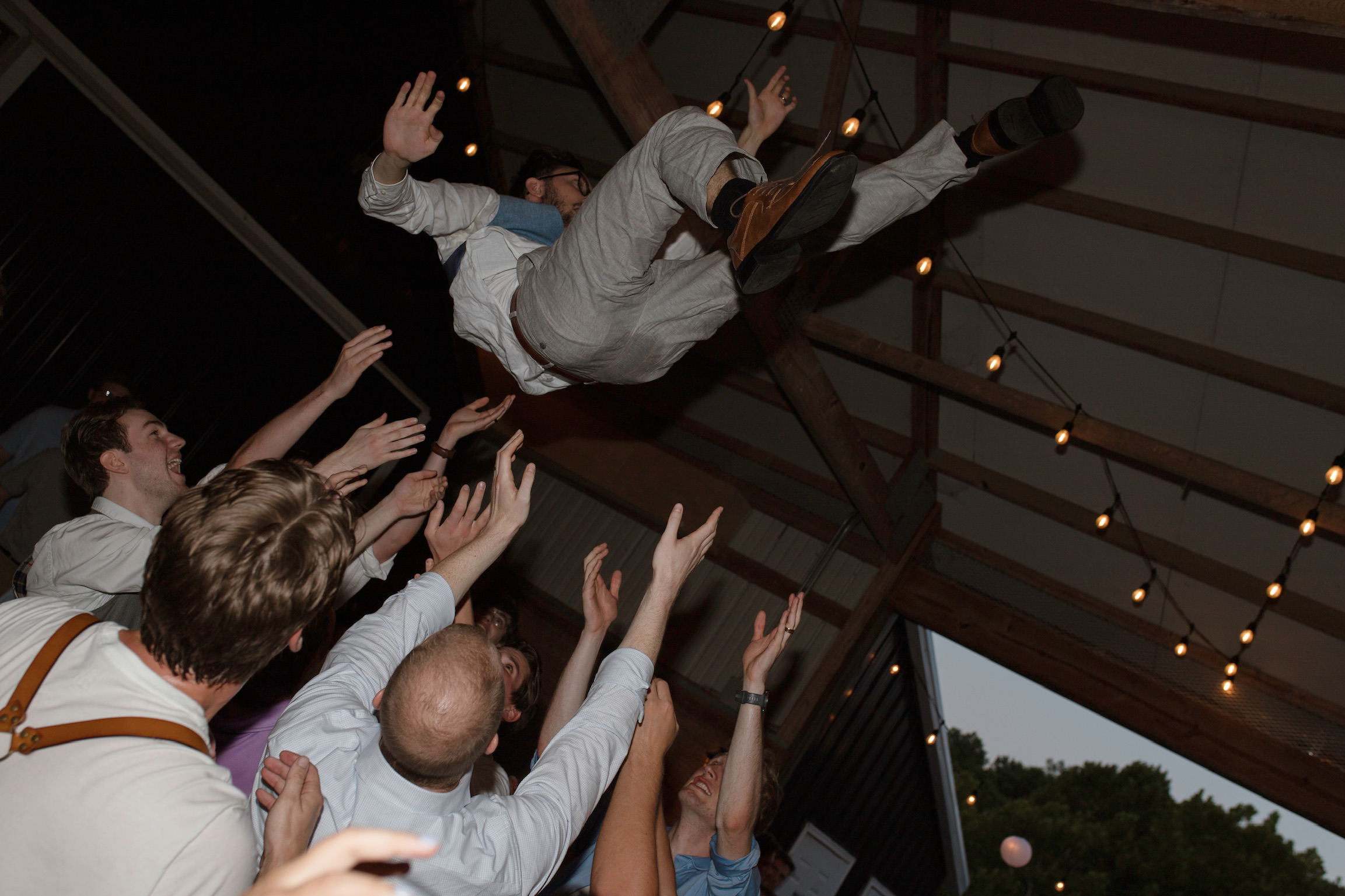 Groom tossed in the air at wedding dance party